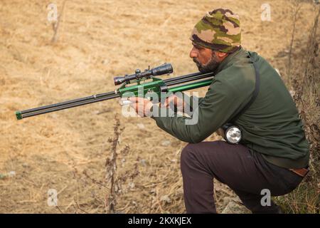 Srinagar, India. 29th Nov 2022. Un ufficiale della fauna selvatica tiene una pistola tranquillizzante mentre prende posizione durante l'operazione di salvataggio a Chadoora Budgam. Gli ufficiali della fauna selvatica hanno detto che il leopardo aveva preso riparo sotto un veicolo, generando panico tra i residenti, più tardi un gruppo di esperti tranquillizzò il leopardo e lo ha spostato in un santuario sicuro. (Foto di Faisal Bashir/SOPA Images/Sipa USA) Credit: Sipa USA/Alamy Live News Foto Stock