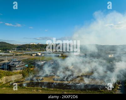 Il fumo da bruciature controllate sorge fuori da una piccola fattoria nella zona rurale Foto Stock