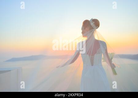 Bella donna in posa in bianco abito da sposa su Santorini Island, Grecia Foto Stock