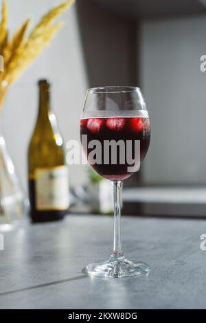 Primo piano in vino rosso in bicchieri con ghiaccio sul tavolo testurizzato Foto Stock