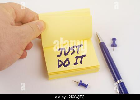 Concetto di business e finanza. L'uomo sta sfogliando attraverso gli adesivi, il foglio dice - BASTA FARLO Foto Stock