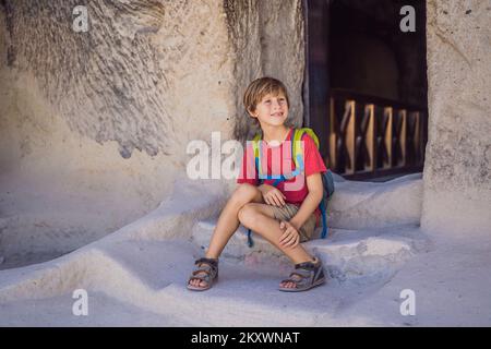 Ragazzo turistico esplorando la valle con formazioni rocciose e grotte delle fate vicino a Goreme in Cappadocia Turchia Foto Stock