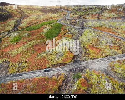 Auto che guida attraverso gli altopiani islandesi su una strada di ghiaia in autunno Foto Stock