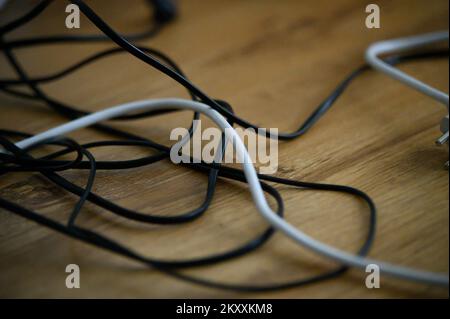 Cavo disordine caotico da più fili elettrici cavi di prolunga e multi-spine di contatto sul pavimento in legno o sfondo tabella Foto Stock