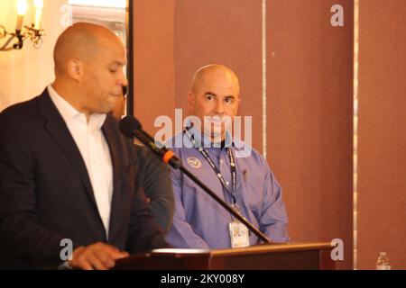 Newark, N.J., 12 novembre 2012 Jose Girot, un ufficiale di coordinamento federale dispiegato come ufficiale di collegamento a Newark per la risposta all'uragano Sandy, guarda su come il sindaco Cory Booker annuncia l'apertura di un Centro di recupero di emergenza presso il Centro di Assistenza della Comunità di cuore disposto a Newark, N.J. New Jersey Hurricane Sandy. Fotografie relative a disastri e programmi, attività e funzionari di gestione delle emergenze Foto Stock