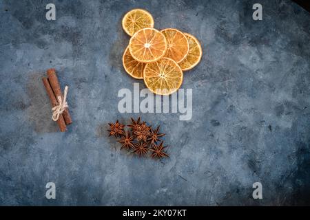 Composizione natalizia con fette di arance essiccate, anice stelle e cannella stick su sfondo grigio testurizzato. Immagine piatta dall'alto con centro di copiatura Foto Stock