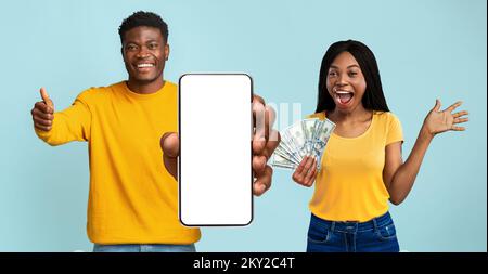 I millennial neri sono molto gioiosi e hanno in mano un sacco di denaro contante e smartphone Foto Stock