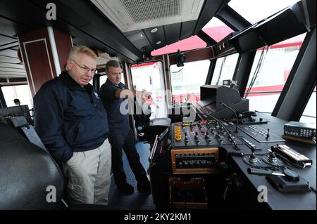 New York, N.Y., 1 dicembre 2012 Michael Byrne, ufficiale di coordinamento federale, ha lasciato, ottiene un giro di Marine 9 Fire Boat II dal pompiere Brian Masterson. Il motoscafo antincendio, che serve tutto il porto di New York, è attraccato presso la FDNY Marine 9 Barracks presso l'ex sito Navy Homeport a Stapleton, Staten Island. Il piroscafo ricevette qualche danno dall'impennata della tempesta a seguito dell'uragano Sandy. New York, NY, 1 dicembre 2012--ufficiale federale di coordinamento Michael Byrne, a sinistra, ottiene un giro di Marine 9 fuoco barca dal pompiere Brian Masterson. Il motoscafo antincendio, che serve tutto il porto di New York, è attraccato a Foto Stock