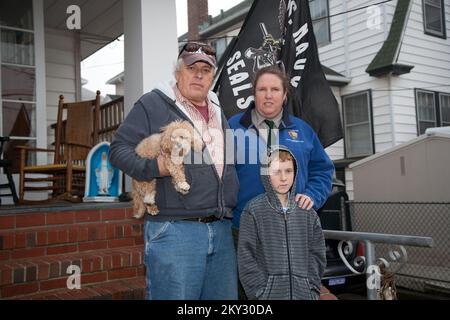 Coney Island, N.Y., 4 dicembre 2012 la famiglia Kirk, Dan, Bailey (il cane), Rita e Kennedy, posano davanti alla casa che stanno restaurando dopo i danni di tempesta. FEMA collabora con vari partner, tra cui governi federali, statali, locali e tribali, organizzazioni volontarie basate sulla fede e sulla comunità, insieme al settore privato, per assistere i residenti colpiti dall'uragano Sandy. L'uragano Sandy di New York. Fotografie relative a disastri e programmi, attività e funzionari di gestione delle emergenze Foto Stock