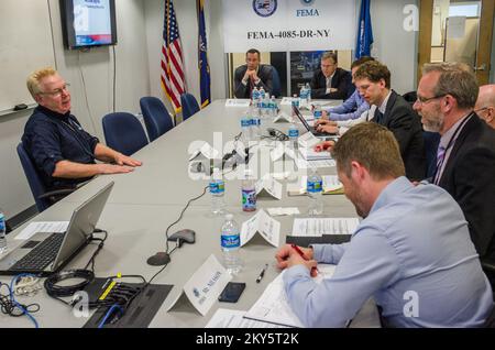 Queens, N.Y., 25 aprile 2013 la FEMA ha ospitato funzionari municipali e di gestione delle emergenze di Stoccolma, Svezia presso il JFO (New York Joint Field Office) per informarli sulle operazioni di ripristino di emergenza per l'uragano Sandy. Michael Byrne, funzionario federale di coordinamento, fornisce informazioni ai visitatori sulle operazioni di risposta e recupero della FEMA. K.C.WILSEY/FEMA. L'uragano Sandy di New York. Fotografie relative a disastri e programmi, attività e funzionari di gestione delle emergenze Foto Stock