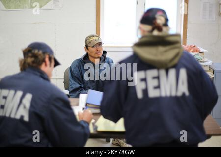 Alakanuk, Alaska, 16 luglio 2013 FEMA Individual Assistance Specialist Toby Rice and Tribal Liason Wendy Stevens talk registration options at a improvvised disaster assistance registration session in the Town Hall offices with disaster survivors. La FEMA sta rispondendo e ha un team che lavora con i sopravvissuti alle catastrofi, lo Stato dell'Alaska e le aree regionali di partecipazione educativa (REAA) designate. Adam DuBrowa/FEMA. Fotografie relative a disastri e programmi, attività e funzionari di gestione delle emergenze Foto Stock