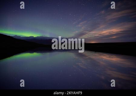 Le aurore danzano sopra Jökulsárlón, proiettando un magico bagliore sulla laguna del ghiacciaio e sugli iceberg Foto Stock