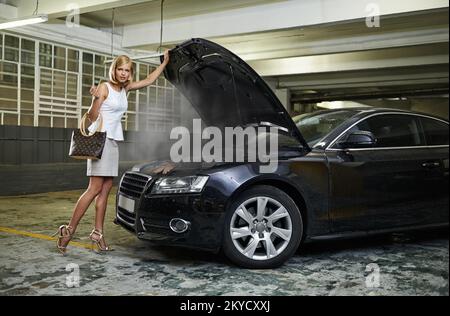 OH caro. Tutta la lunghezza di una giovane donna in piedi accanto alla sua auto rotta. Foto Stock