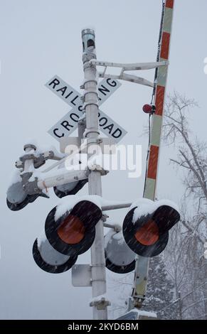 3 strada che attraversa il cancello, segno, e luci di avvertimento alla 3rd strada che attraversa la ferrovia, in una giornata nevosa, a Troy, Montana. Burlington Northern e Santa Foto Stock