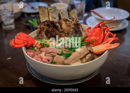 Versione esotica gourmet della zuppa di pho vietnamita con aragosta, costolette e filetto mignon in un grande recipiente in un ristorante, San Mateo CA Foto Stock