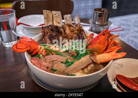 Versione esotica gourmet della zuppa di pho vietnamita con aragosta, costolette e filetto mignon in un grande recipiente in un ristorante, San Mateo CA Foto Stock