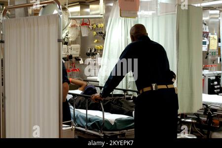 Uragano Katrina/Hurricane Rita, New Orleans, 6 ottobre 2005 - il personale del corpo medico a bordo della nave ospedaliera USNS Comfort da 1.000 posti letto, ora ancorato qui e fornendo le strutture mediche critiche e il personale per aiutare ad alleviare le risorse mediche della città, tendono ad un paziente ricoverato di recente. La USNS Comfort è arrivata a New Orleans dopo un dispiegamento di 30 giorni a Pascagoula, signora, subito dopo l'atterraggio dell'uragano Katrina il 30 agosto. Vinci Henderson/FEMA Foto Stock