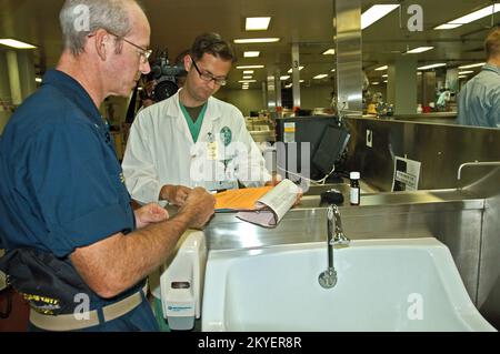 Hurricane Katrina/Hurricane Rita, New Orleans, 6 ottobre 2005 - Un corpsman della Marina (a sinistra) e un medico della Louisiana state University vanno sopra la cartella medica di un paziente ammesso sul Comfort USNS, Una nave ospedaliera ora ormeggiata qui per fornire sostegno alle strutture mediche della città che hanno subito danni paralizzanti causati dagli uragani Katrina e Rita. Il personale medico dell'Università sta aiutando a fornire il trattamento alle persone che hanno bisogno di cure mediche inviate a questa struttura medica galleggiante. Vinci Henderson/FEMA Foto Stock