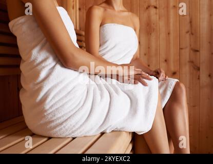 Godetevi la sauna. Immagine ritagliata di due amici seduti nella sauna insieme. Foto Stock