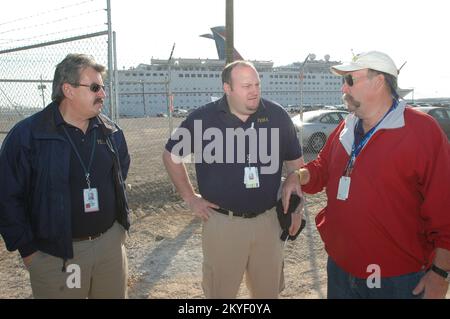 Uragano Katrina, Pascagoula, signorina, 30 ottobre 2005 -- il direttore della filiale di FEMA Mike Madden (a sinistra) e il direttore operativo Bob Fenton (al centro) parlano con il direttore aggiunto della filiale III Jeff Prevey di fronte alla nave da crociera di Carnevale Holiday. La nave, ora ormeggiata al porto di Pascagoula, è utilizzata come alloggio temporaneo per i residenti del Mississippi sfollati dall'uragano Katrina. Foto Stock