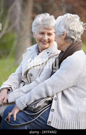 Ritrovo con un vecchio amico. Due donne anziane sorridenti che si siedono insieme all'aperto. Foto Stock