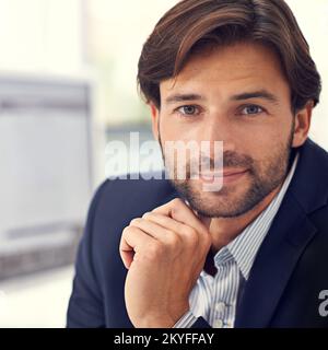 Qui, non è mai solo un altro giorno in ufficio. Ritratto di un bell'uomo seduto alla scrivania in un ufficio. Foto Stock