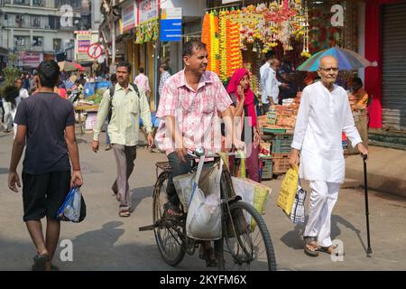 Scena di strada in Bhuleshwar / Kalbadevi mercato zona a Mumbai, India, un ciclista di passaggio Foto Stock