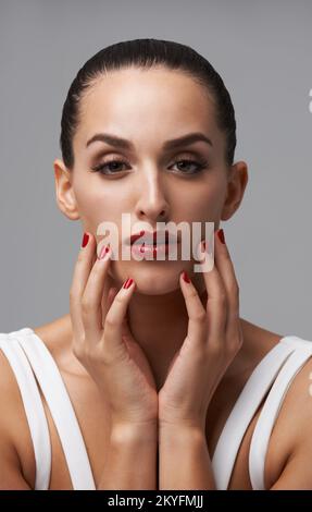 Vive la vita colorata. Studio ritratto di una giovane donna che indossa rossetto e smalto per unghie. Foto Stock