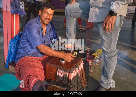 Un uomo polacco-wallah o shoeshine, un migrante da Bihar nell'India del Nord, lucidando la scarpa di un cliente alla stazione di Matunga a Mumbai, in India Foto Stock