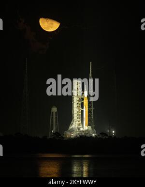 Merritt Island, Stati Uniti. 14th Nov 2022. La Luna si vede innalzarsi sopra il razzo Space Launch System (SLS) della NASA con la navicella Orion a bordo al Launch Pad 39B mentre i preparativi per il lancio continuano, lunedì 14 novembre 2022, al Kennedy Space Center in Florida. La missione di volo Artemis i della NASA orbiterà intorno alla luna come primo passo per gli Stati Uniti per inviare gli astronauti di nuovo alla superficie lunare dopo 50 anni. NASA Photo by Bill Ingalls/UPI Credit: UPI/Alamy Live News Foto Stock