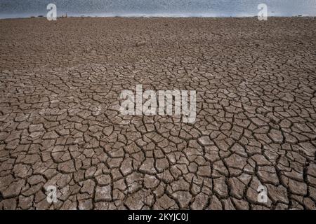 Serbatoio sau al 30% della sua capacità d'acqua. Suolo sabbioso incrinato a causa della scarsità d'acqua in alcune zone della palude di Sau, Vilanova de Sau, Spagna, il 29 novembre 2022. © Joan Gosa 2022/Alamy Foto Stock