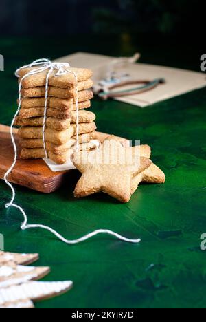 Biscotti di Natale fatti in casa a forma di stella sullo sfondo verde scuro Foto Stock