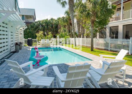 Destin, Florida- piccola piscina con float piscina flamingo con gambe in un cortile con recinto picket. Ci sono quattro poltrone nella parte anteriore di fronte alla p Foto Stock