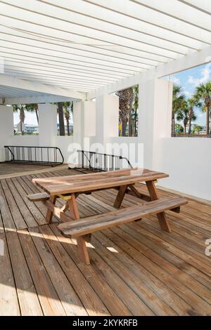 Destin, Florida- tavolo di legno con sedie vicino alle finestre aperte con vista all'aperto. Tavolo da pranzo su un pavimento in legno e pareti dipinte di bianco. Foto Stock