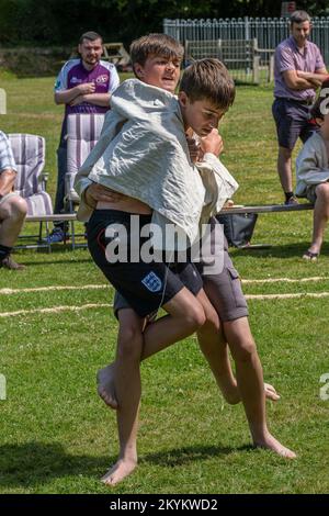 Due giovani fratelli adolescenti che gareggiano nel torneo di Wrestling della Grande Cornovaglia sul pittoresco villaggio verde di St Mawgan a Pydar in Cornovaglia Foto Stock