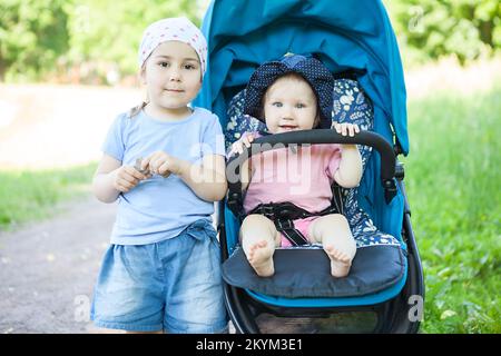 Sorelle di diverse età in una passeggiata nel parco, ragazze di uno e tre anni insieme Foto Stock