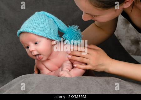 Rivne, Ucraina 25 aprile 2022: Un bambino neonato con un cappuccio blu giace sullo stomaco, ritratto da vicino. Foto Stock