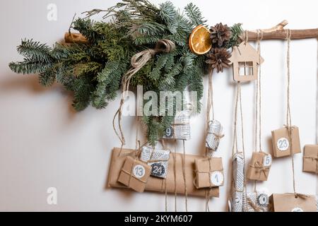 Un calendario dell'avvento natalizio con regali e decorazioni pende su una parete bianca in una stanza. Gorizontal foto Foto Stock