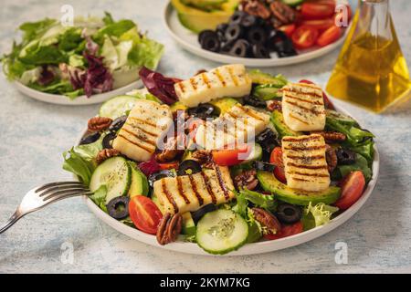 Cucina greca - insalata con formaggio halloumi alla griglia, avocado, noci pecan e pomodori. Foto Stock