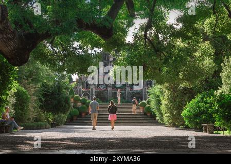 Passeggiate in giardino, vista posteriore in estate di una giovane coppia che cammina su un sentiero nei famosi giardini Italianate di Isola Bella, Lago maggiore, Italia Foto Stock