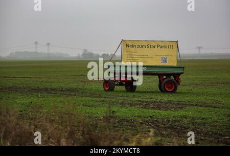 01 dicembre 2022, Sassonia-Anhalt, Gröbers: Un manifesto di protesta contro la zona industriale di Star Park II con l'iscrizione "No a Star Park II" è parcheggiato su un rimorchio in un campo. La zona industriale "Star Park II" di circa 200 ettari vicino a Halle non deve essere costruita. Il consiglio locale di Kabelsketal (Saalekreis) ha deciso contro il progetto. A Kabelsketal si è manifestata resistenza contro l'espansione della zona industriale "Star Park i" da parte del nuovo "Star Park II". Un'iniziativa dei cittadini teme ulteriori oneri per le persone, la natura e l'ambiente attraverso il traffico aggiuntivo e. Foto Stock