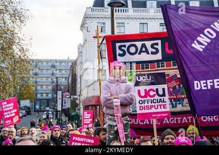 Londra, Regno Unito. 30th Nov 2022. Un manifestante si trova sopra i manifestanti durante il rally. Migliaia di persone si riuniscono al di fuori della stazione di King's Cross a sostegno della più grande passeggiata organizzata dall'Università e dall'Unione universitaria (UCU) per chiedere una retribuzione significativa, per fissare condizioni di lavoro scadenti e tagli alle pensioni. Credit: SOPA Images Limited/Alamy Live News Foto Stock