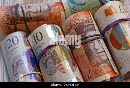 Rolls of British Bank of England banconote tenute insieme da bande elastiche Foto Stock