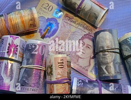 Rotoli di banconote scozzesi britanniche tenuti da fasce elastiche, che circondano una banconota da 20 sterline della Bank of England. Foto Stock