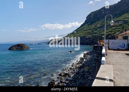 Gente del posto, compreso un pescatore, sul lungomare di Las Aguas, San Juan de la Rambla, Tenerife, Isole Canarie, Spagna, ottobre 2022. Foto Stock