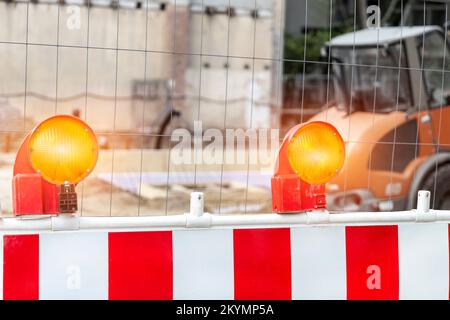 Primo piano vista dettagliata lampeggiatore arancione barriera fotoelettrica di sicurezza contro recinzione area di lavoro cantiere. Attrezzatura di sicurezza lampada fusibile barricata Foto Stock