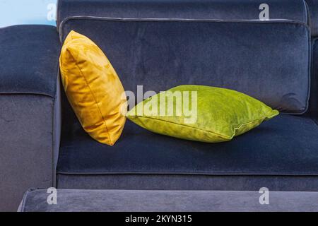 Cuscini in pelle sintetica gialla e verde sul divano Blue Plush Foto Stock