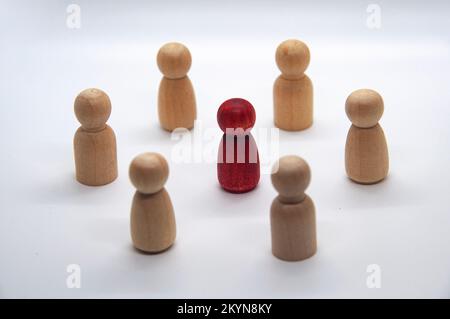 Bambola di legno rosso circondata da un'altra figura di legno. concetto di leadership. Foto Stock