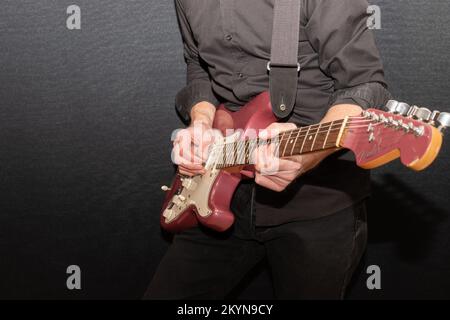 Vaduz, Liechtenstein, 11 gennaio 2022 il musicista suona un Fender Stratocaster USA realizzato 1995 nel colore della nebbia di borgogna Foto Stock