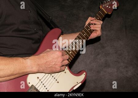 Vaduz, Liechtenstein, 11 gennaio 2022 il musicista suona un Fender Stratocaster USA realizzato 1995 nel colore della nebbia di borgogna Foto Stock